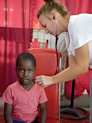 SJC nursing student providing medical exam on a Haitian child