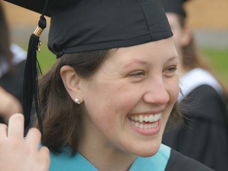 11-year-old Susan Muzzy, wearing a graduation cap and gown, is smiling. Saint Joseph's College of Maine