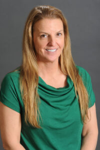 Counseling Center 3 A woman with long, light brown hair wearing a green short-sleeved top, smiling in front of a plain gray background. Saint Joseph's College of Maine