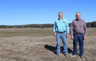 All Roads Lead To The Farm 5 Danny and Jon Shaw stand in a field with blue sky behind.