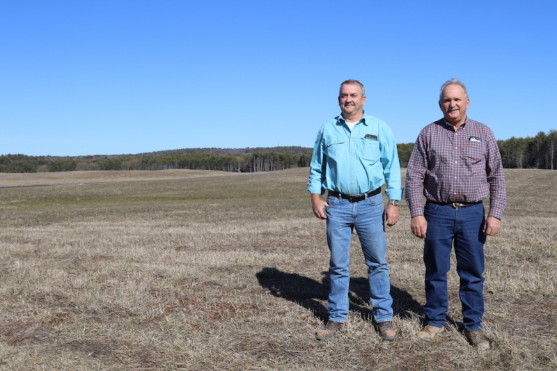 All Roads Lead To The Farm 1 Danny and Jon Shaw stand in a field with blue sky behind.