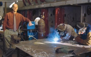 Meet David Morse ’08 7 A man in a red shirt and tie stands next to two individuals in welding gear, working on a large metal sheet in an industrial workshop. Amongst them is David Morse, a distinguished alumni from the class of 2008. Saint Joseph's College of Maine