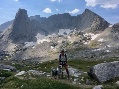 Trail Magic 2 Effie poses with her dog Luna in front of a large glacial field.
