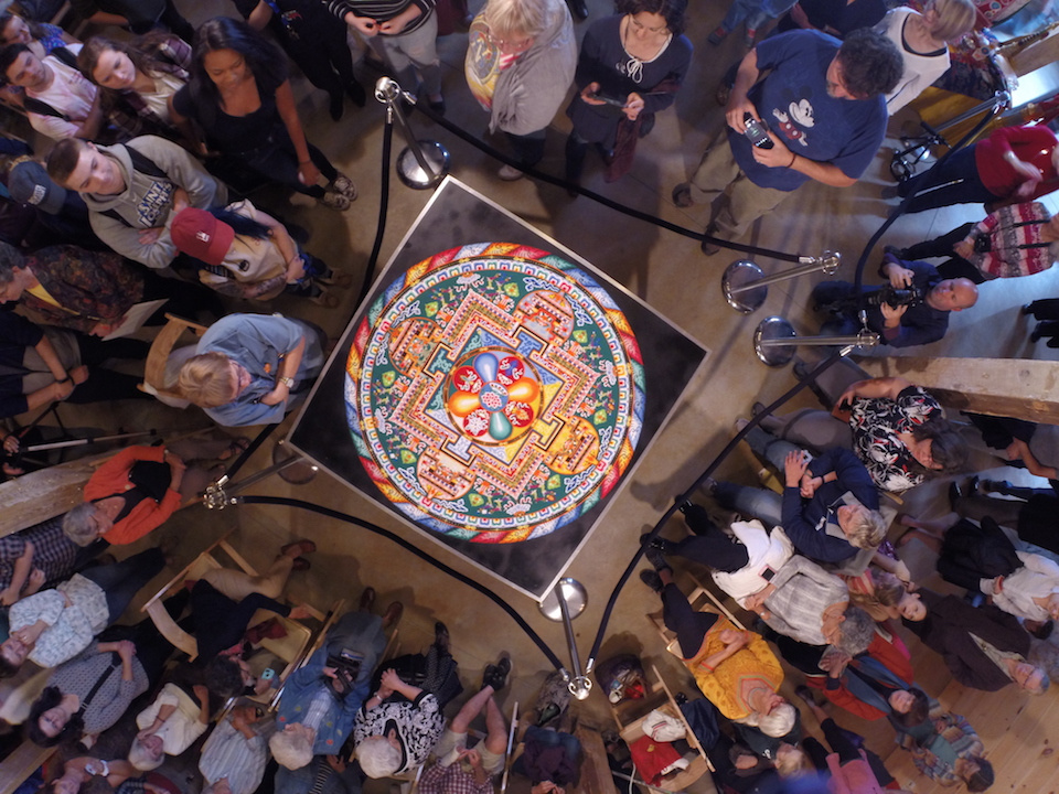 Healing The Earth 1 A crowd of people look at a colorful mandala painting