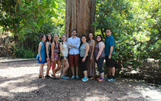 Go Global, Go Granada!: Saint Joseph’s College Students Return From Summer Internship 4 A group of nine people, participating in a Saint Joseph’s College Summer Internship, stand and pose in front of a large tree trunk in a wooded park. Saint Joseph's College of Maine