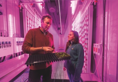 Rising To The Challenge 3 Mark Green holds seedling and talks to Emily Quirion '18 in the Freight Farm