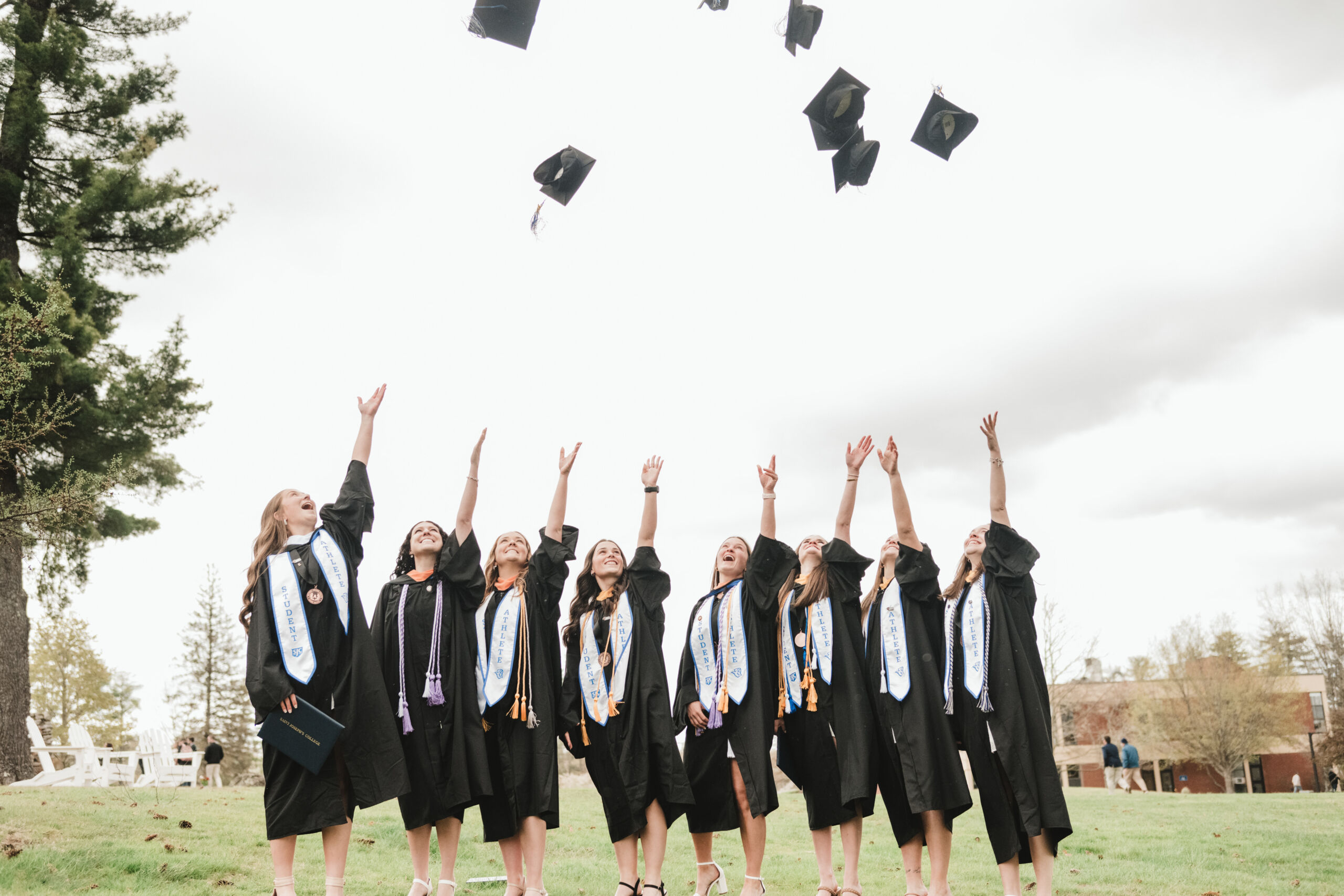 Commencement 10 Graduates in caps and gowns joyfully celebrate their commencement by tossing their caps into the air on a grassy field, marking their achievement together. Saint Joseph's College of Maine