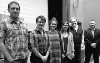 Saint Joseph'S College Gives Overview Of Hydroponics Farm At The Institute For Local Food Systems Innovation 5 A group of six people stands indoors in a line facing the camera, with four men and two women in casual and business attire. A presentation screen and podium are visible in the background, hinting at a discussion on Local Food Systems Innovation at Saint Joseph's College. Saint Joseph's College of Maine