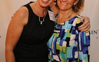 Saint Joseph’s College Honors Catherine Renquin Ryder '81 With The Professional Excellence Award 10 Two women are smiling and standing together in front of a Saint Joseph's College banner. One, Catherine Renquin Ryder, is wearing a black dress, while the other is in a colorful geometric patterned dress. Their joy likely stems from celebrating the Professional Excellence Award at Saint Joseph’s College. Saint Joseph's College of Maine