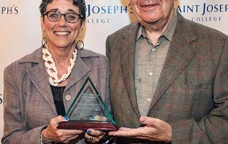 Saint Joseph’s College Honors Cynthia Murray Beliveau ‘70 With The Catherine Mcauley Award 2 Two people stand together holding the prestigious Catherine McAuley Award. They are posing in front of a step-and-repeat backdrop displaying "Saint Joseph's College. Saint Joseph's College of Maine