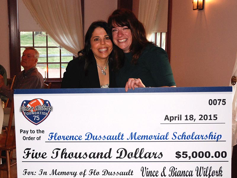 Two women smiling and holding a large ceremonial check for the Florence Dussault Memorial Scholarship worth five thousand dollars, dated April 18, 2015, at Saint Joseph's College of Maine. Saint Joseph's College of Maine
