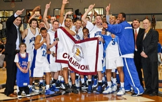 Men'S Basketball Team Wins Championship...and Our Hearts 6 A men's basketball team celebrates on the court, holding a "Champion" banner. Coaches, staff, and a child in a jersey stand with them as they savor their championship win. Some players and coaches raise their hands in victory, capturing the hearts of everyone present. Saint Joseph's College of Maine