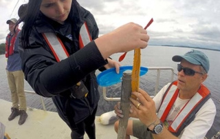 Sjc Science Scholars Program Awarded National Science Foundation Funding 10 Two individuals on a boat, each wearing life vests, are examining and handling scientific equipment while a third person stands nearby. They appear to be involved in field research on water, supported by the National Science Foundation Funding as part of the SJC Science Scholars Program. Saint Joseph's College of Maine