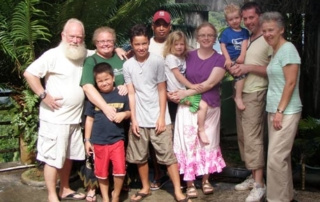 And The Award For The Alumna Living Farthest Away Goes To … 4 Group photo of ten people, including children and adults, standing outdoors in front of lush greenery. Everyone is smiling, several are holding or hugging each other, and the alumna who traveled the farthest away for this gathering is positioned proudly at the center. Saint Joseph's College of Maine