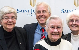 Alumni Profile: Stick To Your Core Values 3 A man and three elderly women, two of whom are wearing religious habits, pose in front of a banner labeled "Saint Joseph's College" to celebrate its core values as part of an alumni profile. Saint Joseph's College of Maine