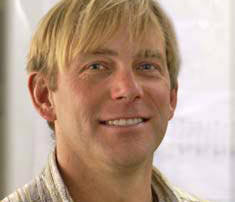 Faculty Expertise Spans The Spectrum 7 A man with short blond hair, wearing a striped shirt, is smiling confidently. His expression suggests a certain expertise, even as he stands in front of a blurry background. Saint Joseph's College of Maine