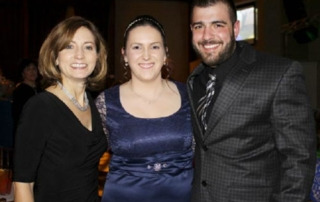 Lauren’s Journey 5 Three people in formal attire stand close together, smiling as they celebrate Lauren's Journey during an indoor event. Saint Joseph's College of Maine