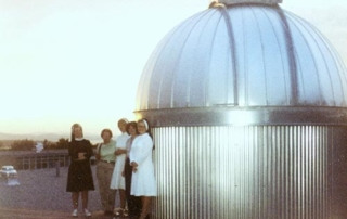 Seeing Stars 1 Four people stand beside a small, metallic observatory dome at sunset, eagerly awaiting their turn to start seeing stars. Saint Joseph's College of Maine