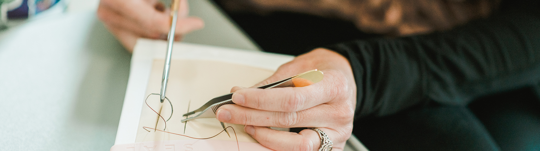 Suturing banner image of FNP student practicing suturing skills